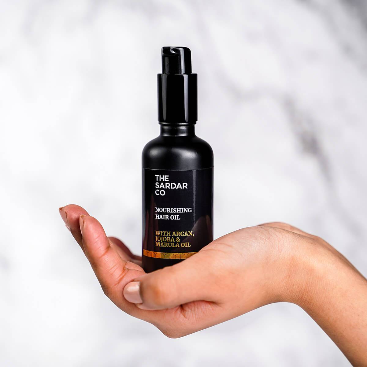 hair oil bottle resting on womans hand