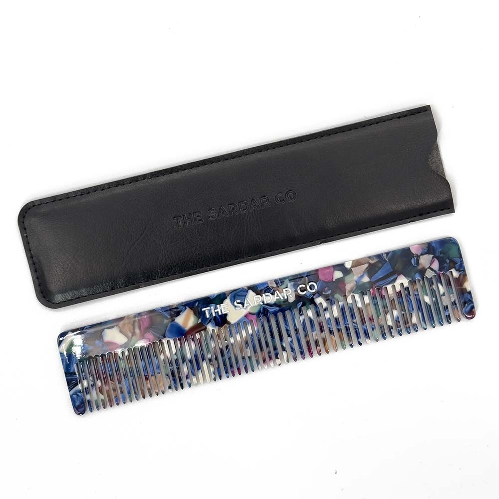 Floral-patterned comb with black leather case on a white background