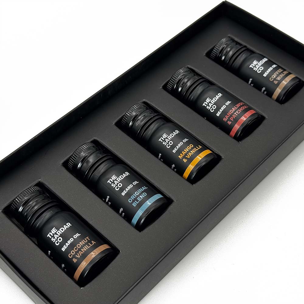 Set of five beard oils bottles in a black box on a white background