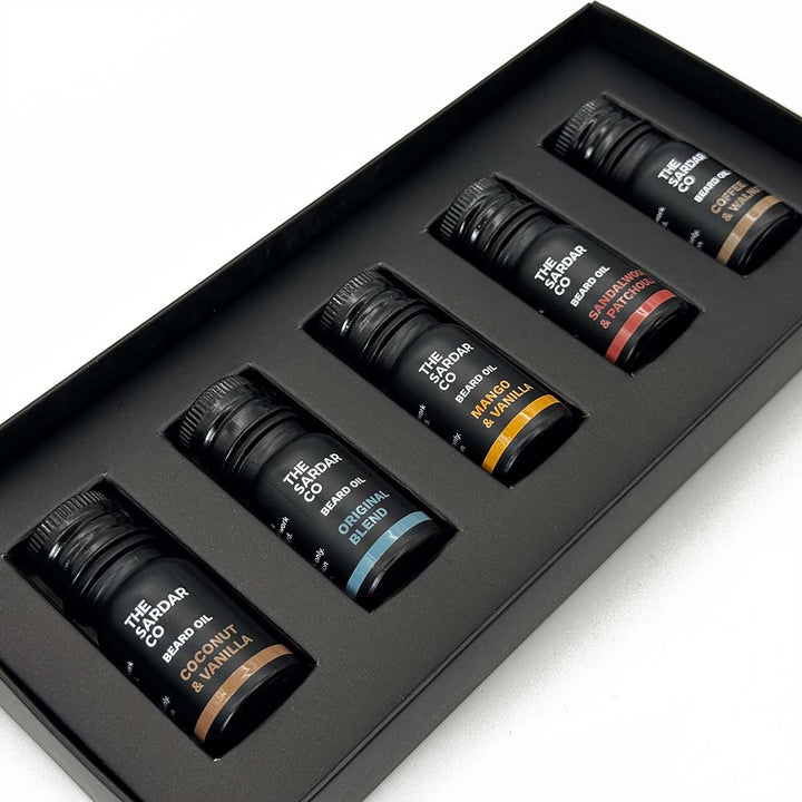 Set of five beard oils bottles in a black box on a white background