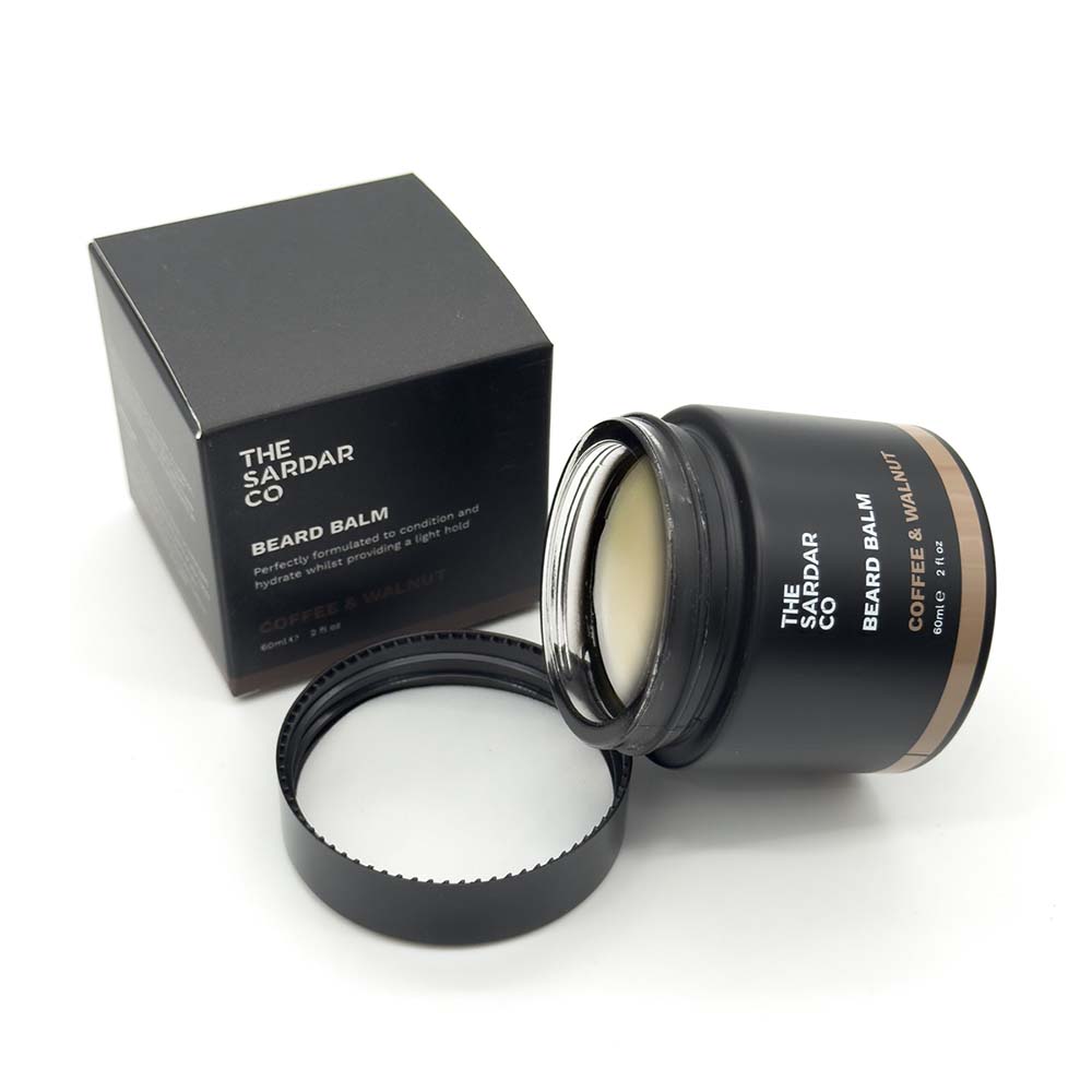 Black beard balm container with open lid and black box labeled 'The Sardar Co' on a white background
