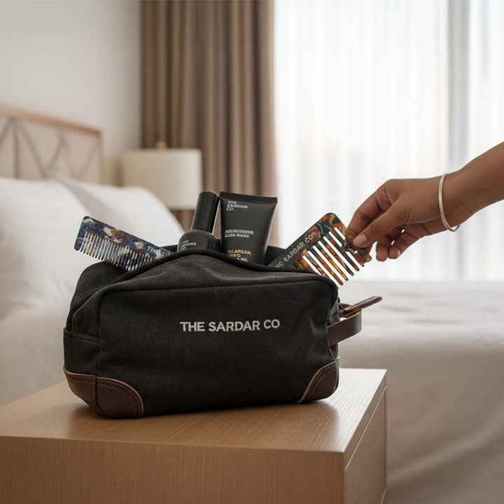 Black toiletry bag with grooming products on a nightstand, featuring &