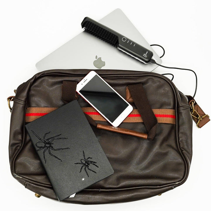 beard straightener brush in a bag being charged from a laptop